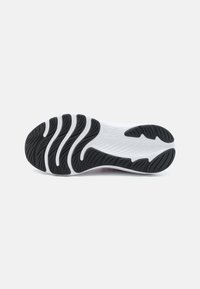 Semelle de chaussure arborant un design ondulé, principalement noire avec des accents blancs, texturée pour l'adhérence avec de profondes rainures et crêtes.