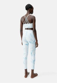 Lichtblauw gemarmerd sportoutfit bestaat uit een cropped sportbh met gekruiste banden en high-waisted leggings met een zachte textuur.