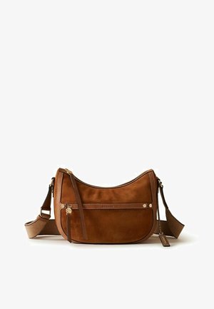 Sac d'épaule en daim marron en forme de croissant avec sangle en tissu réglable, poche avant zippée et petite étiquette en cuir de marque suspendue sur le côté.