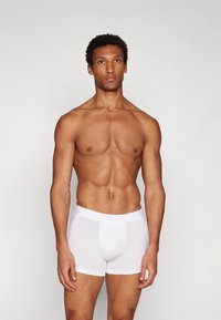 Beli bokser hlačke iz gladkega, raztegljivega materiala. Imajo oprijet kroj, mehak pas in minimalne detajle.