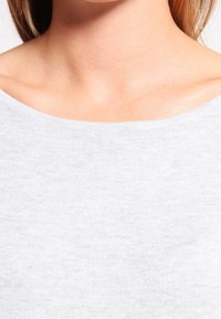 Maglia a costine grigia chiara, con ampio scollo, texture morbida e finitura liscia, che mette in risalto la leggera lucentezza del tessuto.
