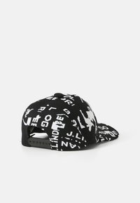 Gorra negra hecha de tela texturizada con texto y patrones gráficos en blanco contrastante. Visera curvada y cierre ajustable de tipo snapback.