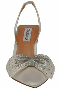 Chaussure plate blanche en satin avec bride arrière et grand nœud orné de cristaux à l'avant, semelle intérieure beige avec label Steve Madden.
