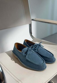 Blauwe suede loafers met een ronde neus, vetersluiting en beige zool. Gestructureerd oppervlak en contrasterende stikdetails.