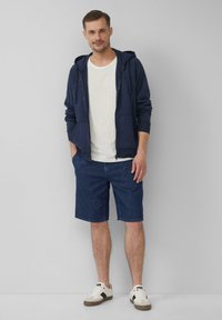 Marine rits hoodie, witte t-shirt en donkerdenim shorts. Sneakers met witte en beige accenten. Eenvoudig en casual kledingontwerp.
