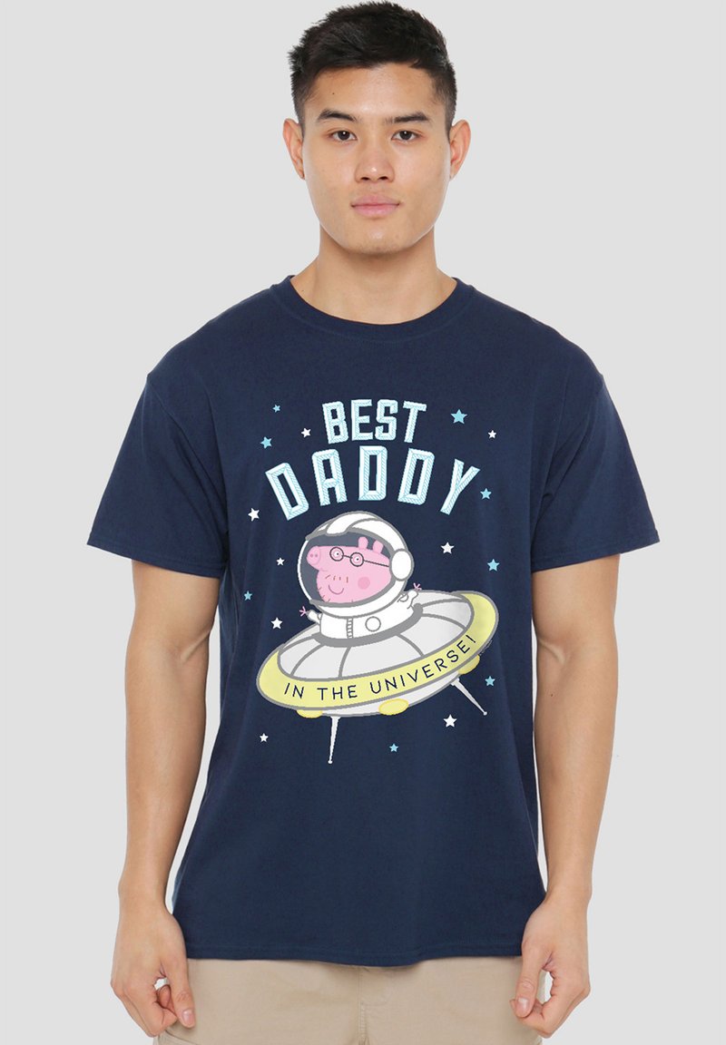 Marineblaues Baumwoll-T-Shirt mit einem Grafik eines Cartoon-Schweins in einem Raumanzug auf einer fliegenden Untertasse, mit dem Text "BESSTER PAPA IM UNIVERSUM" und Sternen.