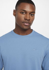 Light blue crewneck T-shirt made of soft fabric, featuring a small embroidered Nike logo on the left chest. Simple, streamlined design.