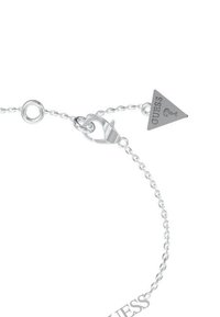 Zilveren armband met een driehoekige hanger waarop "GUESS" is gegraveerd, sluiting met haak en ronde schakels als accent.
