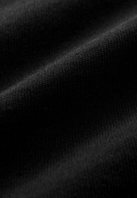 Schwarzer Stoff mit feiner gerippter Textur, der sanfte Kurven und eine weiche, matte Oberfläche zeigt. Das Gesamtbild ist konsistent und einheitlich.
