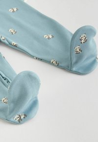 Pijamas de algodón azules con estampado de pandas, con pies redondeados y cierre a presión a lo largo del costado. Textura suave con un diseño juguetón.