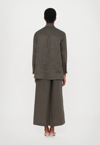 Completo due pezzi verde scuro con una maglietta a maniche lunghe, dalla vestibilità ampia, e pantaloni a gamba larga realizzati in tessuto testurizzato.