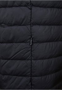 Chaleco acolchado negro con diseño de acolchado, cuenta con costuras horizontales y un cierre de toggle en el cuello. Tejido liso e insulated.