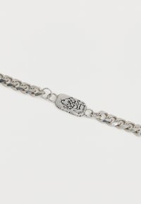 Ασημένιο βραχιόλι αλυσίδα με κεντρικό έμβλημα κεφαλής τίγρη με χαραγμένες λεπτομέρειες, τοποθετημένο σε απλό λευκό φόντο.