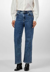 Siniset korkeavyötäröiset farkut suoran lahkeen leikkauksella. Niissä on etutaskut, kontrastivärinen ompelu ja nappisuljenta.