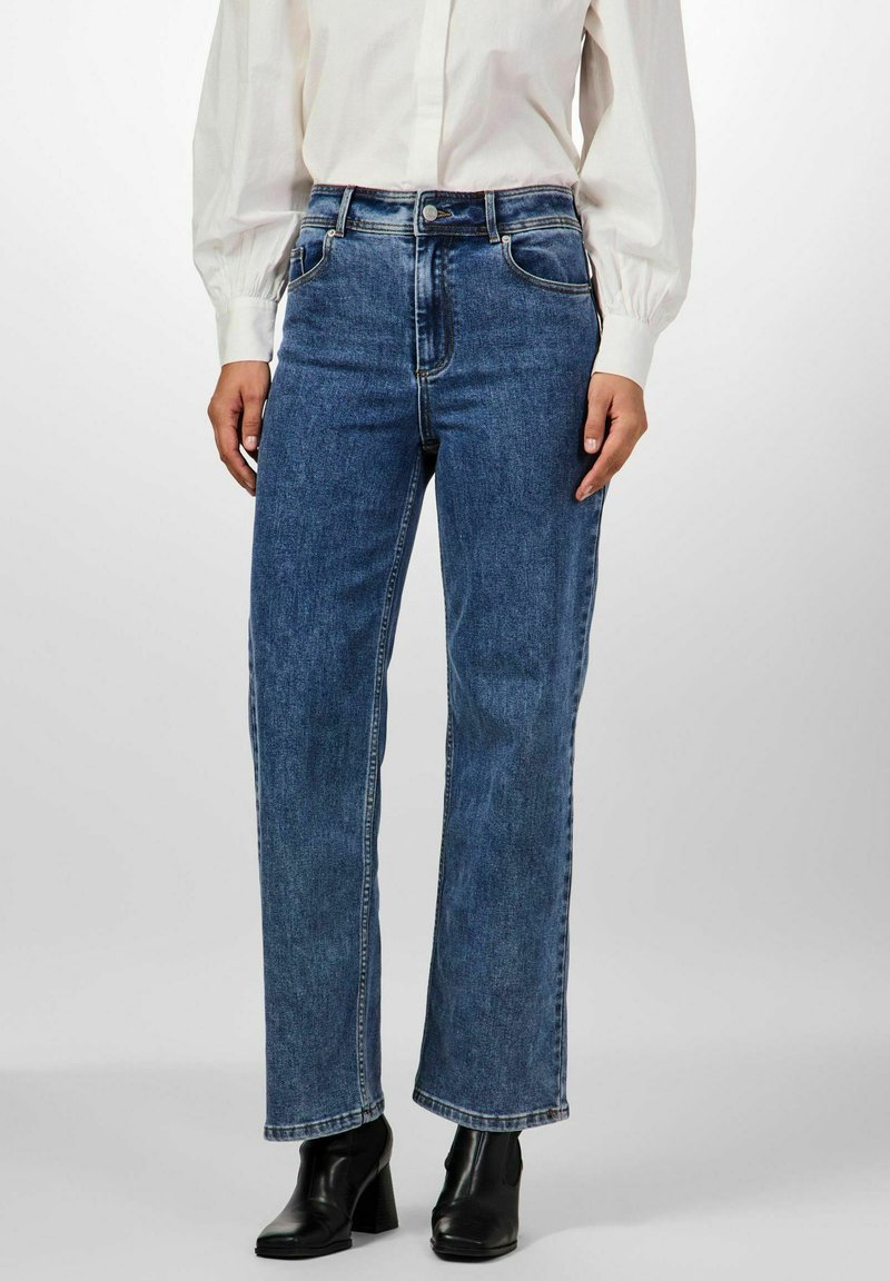 Siniset korkeavyötäröiset farkut suoran lahkeen leikkauksella. Niissä on etutaskut, kontrastivärinen ompelu ja nappisuljenta.