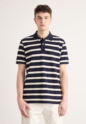 Marineblau und creme gestreiftes Poloshirt mit Kragen und kurzen Ärmeln. Mit einem kleinen gestickten Logo auf der linken Seite. Weicher Stoff.