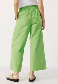 Pantalons larges verts en tissu léger, dotés d'une taille élastique et d'une texture lisse avec une finition unie.