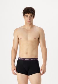Boxerbrief neri con una cintura elastica bordeaux con il logo "HUGO". Finitura in tessuto liscio, design aderente e lunghezza fino a metà coscia.