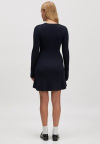 Marineblaues Rippstrickkleid mit langen Ärmeln, taillierter Oberteil, ausgestelltem Rock und rundem Ausschnitt. Mit vertikalen Strukturdetails.