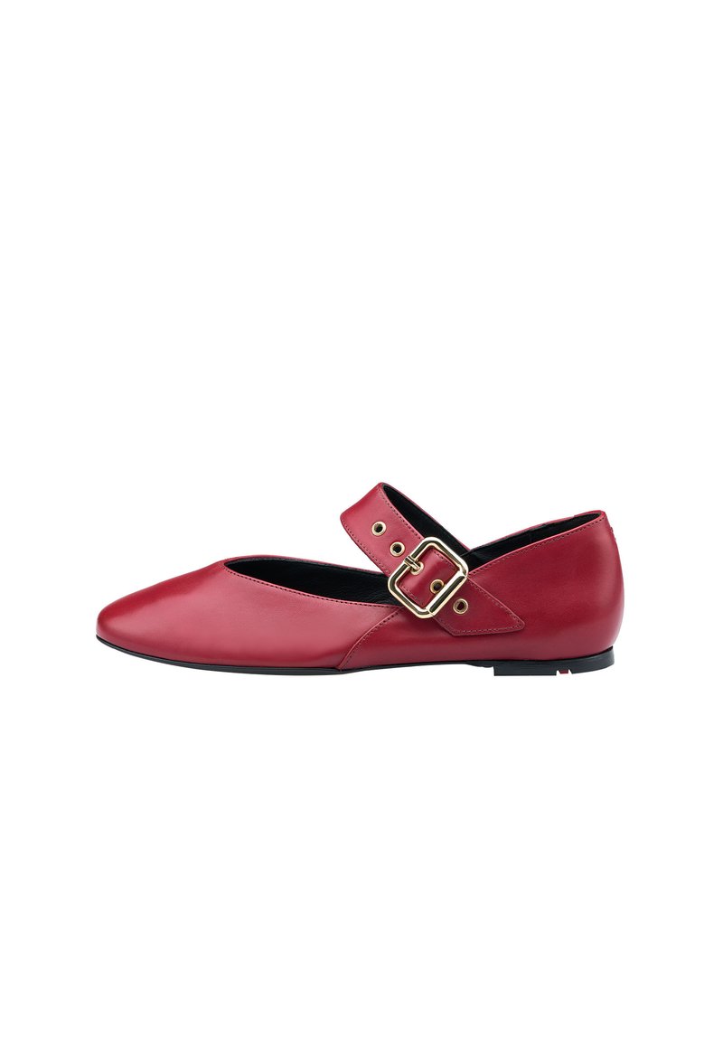 Botte plate en cuir rouge avec un bout pointu et une sangle latérale avec une boucle en or. Texture lisse et semelle noire à profil bas.
