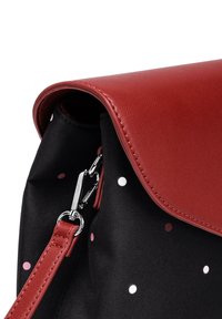 Červená taška z faux kůže s černým textilním tělem zdobeným vícolorými tečkami. Stříbrné kování, součástí je odnímatelný popruh.