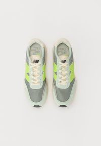 Light gray sneakers with green accents, mesh and suede materials, cream laces, rounded toe, logo on the side, and a textured sole.