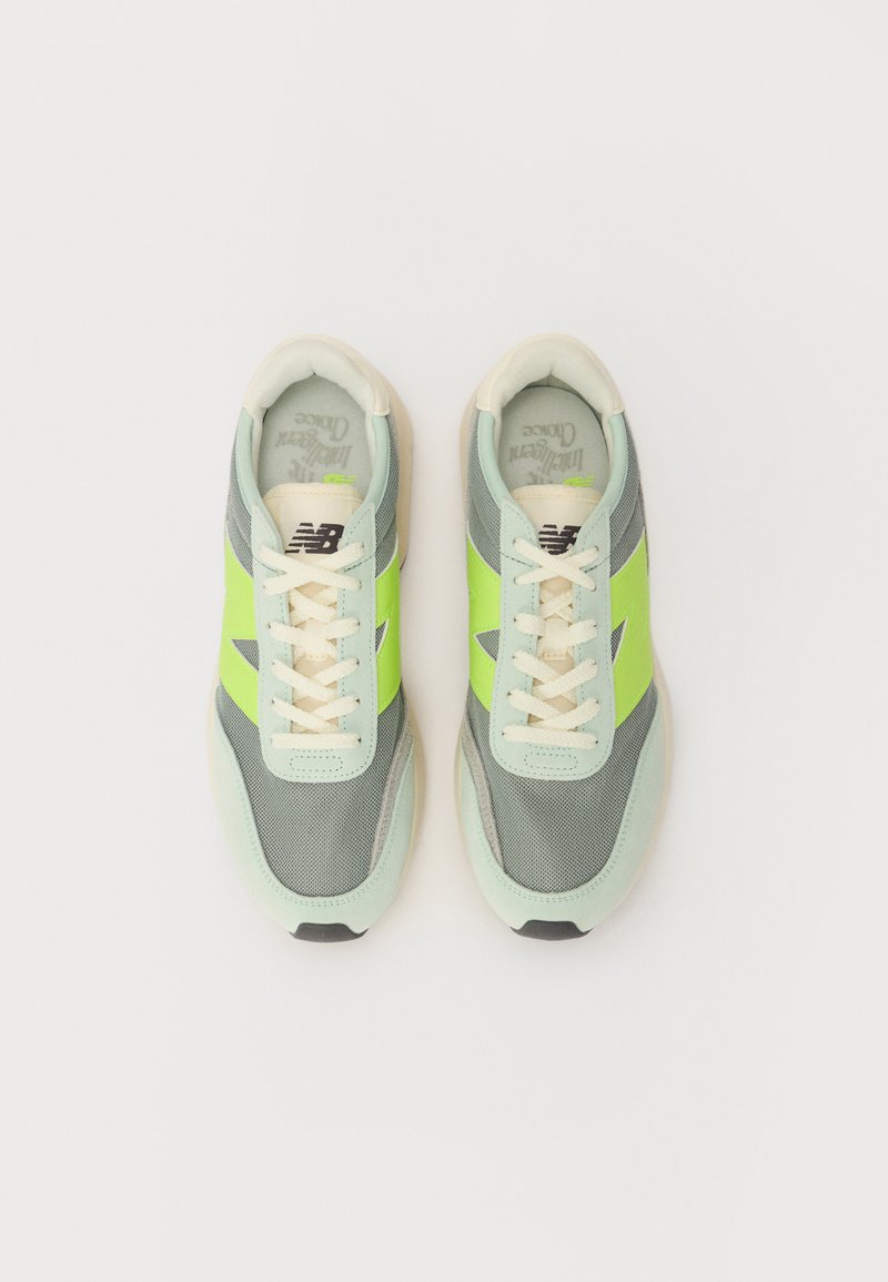 Baskets gris clair avec des accents verts, en mesh et en daim, lacets crémeux, bout arrondi, logo sur le côté et semelle texturée.