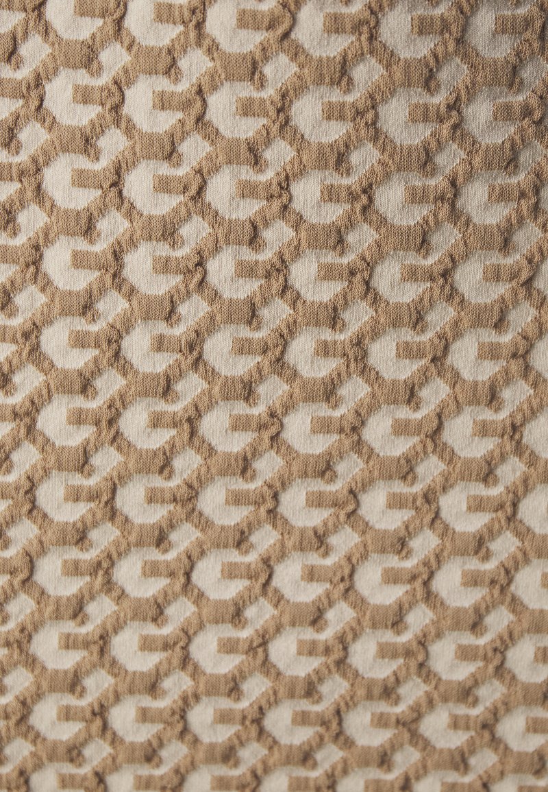 Textil mit einer strukturierten Oberfläche und einem geometrischen Muster in Beige und Hellbraun, mit erhabenen Elementen, die Tiefe und Kontrast schaffen.