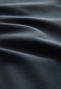 Svart, mjukt tyg med mjuk fall och subtil glans, med mjuka vågor och lätt texturvariation.