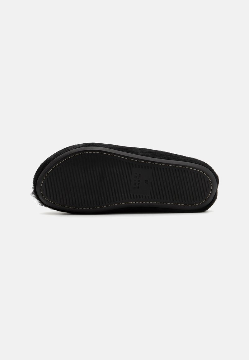 Scarpa da casa foderata in pelliccia nera con suola in gomma testurizzata, caratterizzata da motivi a coste e cuciture a contrasto lungo il bordo. Taglia segnata 36.