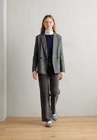 Hallhallane bleiser sinise sviitriga, kombineeritud tumedate hallide laiad püksid ja hallide tossudega. Minimalistlikud detailid, puhtad jooned ja siledad tekstuurid.