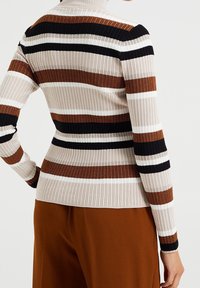 Maglione a collo alto a coste con righe verticali in beige, marrone, nero e bianco. Design aderente con maniche lunghe.