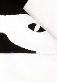 Czarna i biała dzianina o odważnym wzorze z zaokrąglonymi kształtami i motywami oczu, charakteryzująca się miękką teksturą i kontrastującymi kolorami.