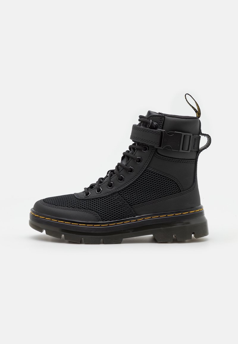 Botte montante noire avec panneaux en mesh, devant à lacets, bride réglable avec boucle, languette de traction et semelle épaisse rainurée avec surpiqûres jaunes.
