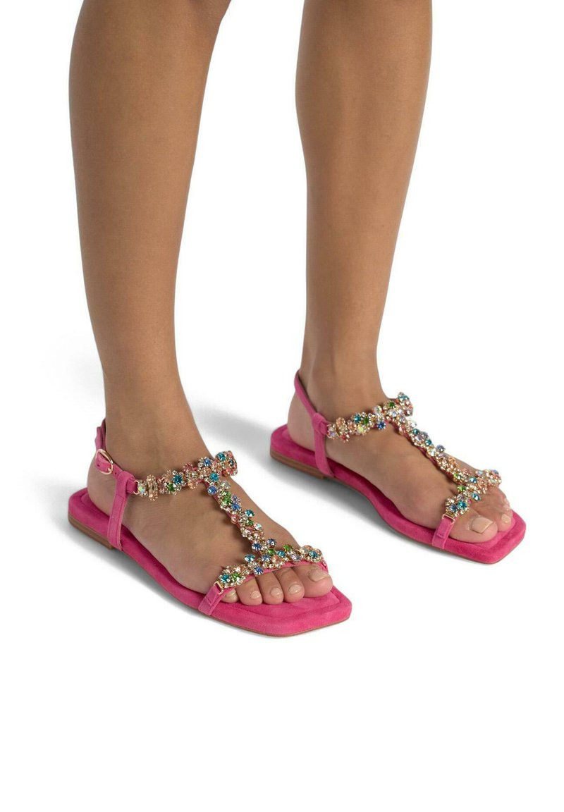 Sandali in suede rosa con suola piatta, caratterizzati da un T-strap con perline decorato con gemme colorate. Fibbia regolabile alla caviglia.