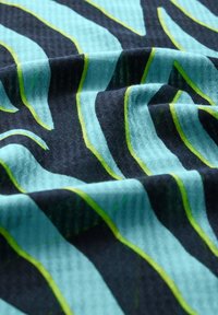 Stof med et bølget mønster i teal og sort med lysegrønne accenter. Teksturen virker struktureret og let reflekterende.