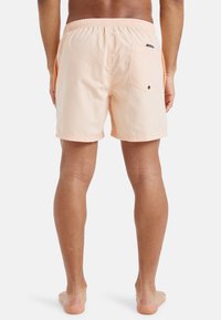 Bañador de melocotón con cinturilla elástica, bolsillo lateral y trasero. Tejido ligero con una textura suave, diseño hasta la rodilla.