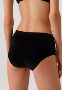 Zwarte katoen boyshorts met een gegolfde rand langs de taille en beenopeningen. Glad aanvoelend met een strakke pasvorm, van achterzijde bekeken.