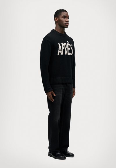 Fekete kötött pulóver, amelyen a "APRÈS" szó krémszínben szerepel, sötét, egyenes szárú nadrággal �és fekete cipővel párosítva. Egyszerű, minimalista dizájn.
