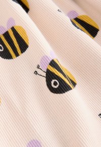 Tissu côtelé rose clair avec un motif de petites abeilles dessinées avec des rayures noires et jaunes et des ailes violettes.