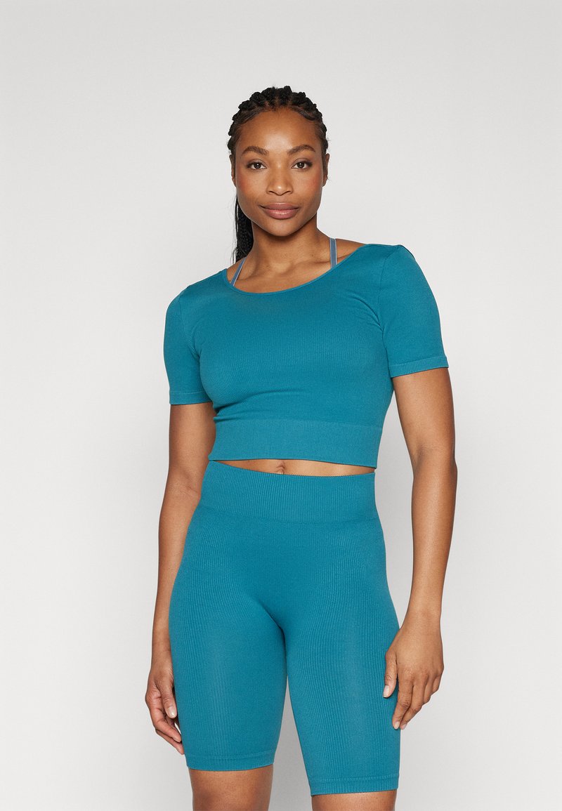 Teal ribbed activewear set featuring a cropped top with short sleeves and high-waisted shorts, made from a smooth, stretchy fabric.