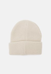 Knit beanie in light beige, featuring a ribbed texture and a folded cuff. The top is rounded and seamless for a fitted look.