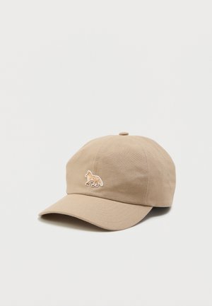 Beige baseballkeps med rund krona, böjd skärm och en broderad räv-emblem på framsidan. Tillverkad av ett texturerat tyg.