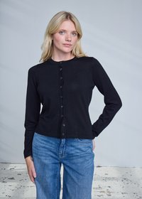 Cardigan nero a maniche lunghe con scollo rotondo, chiusura con bottoni e tessuto liscio, abbinato a jeans a gamba larga di colore azzurro chiaro.