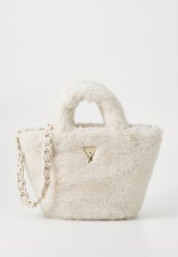 Sac en fausse fourrure de couleur blanc cassé avec un logo doré triangulaire, deux poignées courtes et une bandoulière tressée. Surface texturée.