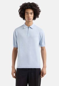 Polo shirt azzurro chiaro a maniche corte con colletto con zip e una texture liscia e traspirante. Design minimalista senza motivi o accenti.