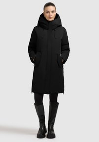 Black insulated coat with a hood, featuring a front zipper, side pockets, and elastic drawstrings; paired with knee-high black boots.