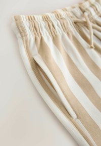 Leichte Jogginghosen aus Baumwolle mit vertikalen beige-weißen Streifen, ausgestattet mit einem elastischen Bund und einem Kordelzug für eine verstellbare Passform.