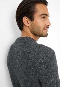 Grau gestrickter Pullover mit einer gefleckten Textur, rundem Halsausschnitt und kurzen, eng anliegenden Ärmeln. Das Design bietet einen lockeren Schnitt und gerippte Bündchen.