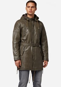 Olivgrön läderjacka med huva, quiltade axelprydnader, justerbara dragsko, bälte i midjan och framfickor med dragkedja.